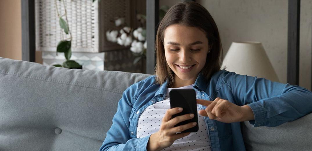 A Millennial reviews her 爱尔兰共和军 account on her phone with Patelco Online.